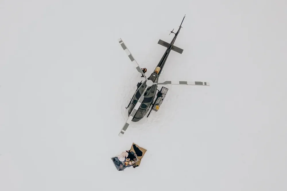 Schwarzer Hubschrauber auf schneebedecktem Gipfel, Hochzeitsreportage MOKATI